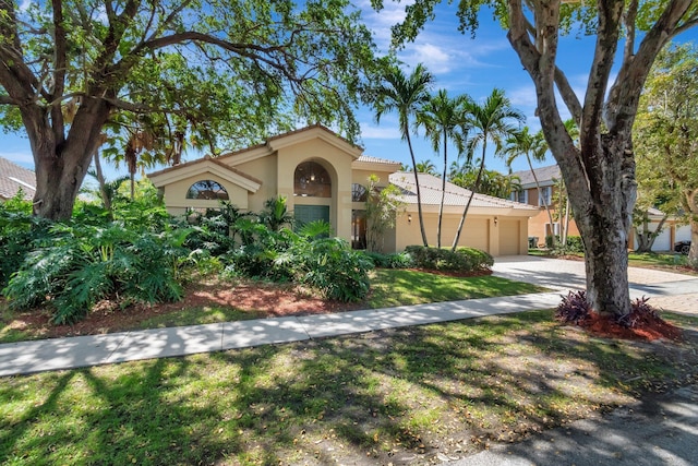 mediterranean / spanish-style home with stucco siding, a garage, driveway, and a tile roof