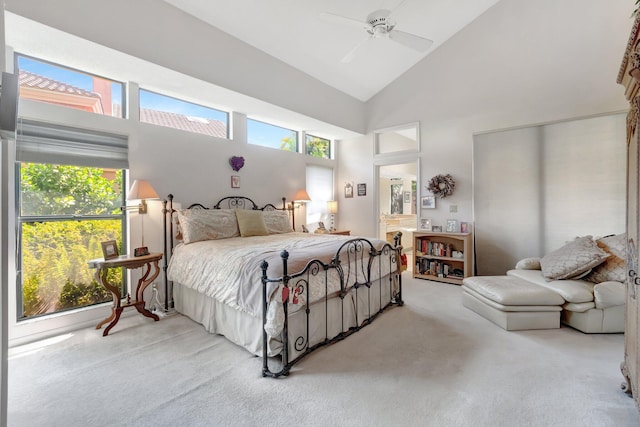 carpeted bedroom featuring ensuite bath, multiple windows, a ceiling fan, and high vaulted ceiling