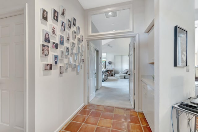 corridor with light tile patterned flooring, light colored carpet, and baseboards