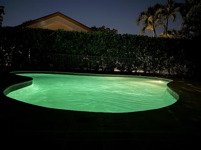 pool at twilight featuring a fenced in pool and fence