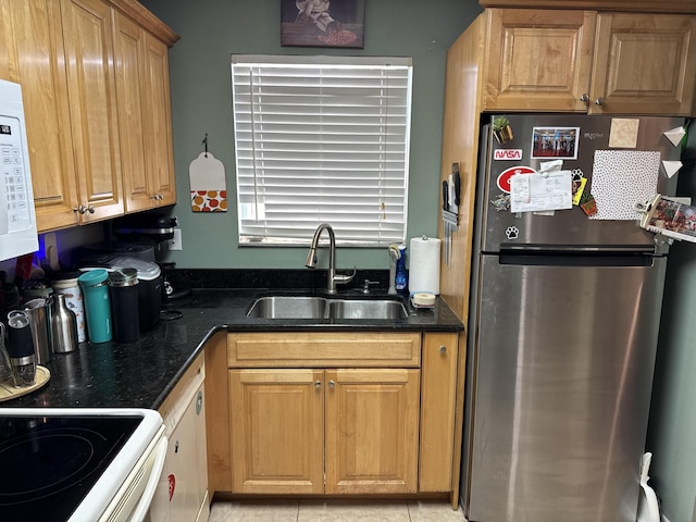 kitchen featuring a sink, dark stone counters, white microwave, and freestanding refrigerator