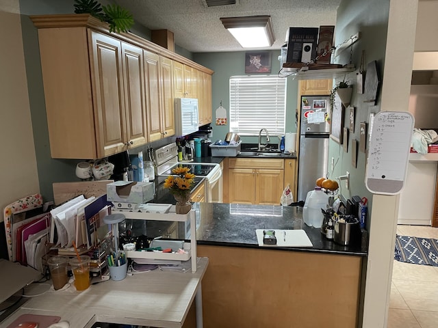 kitchen with dark countertops, light tile patterned flooring, white appliances, a textured ceiling, and a sink