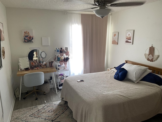 bedroom with a ceiling fan, wood finished floors, and a textured ceiling