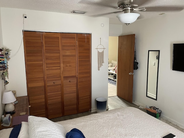 bedroom featuring a closet, visible vents, a textured ceiling, and ceiling fan