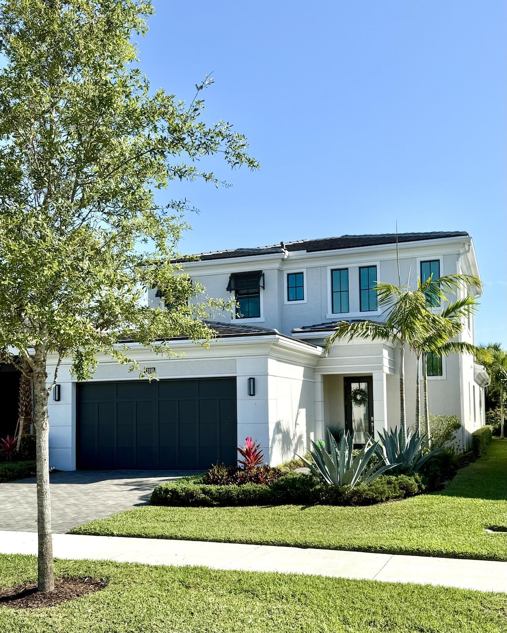 view of front of house featuring stucco siding, a front yard, and driveway