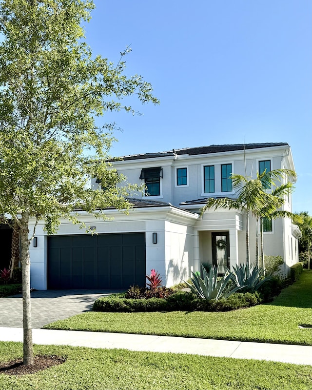 view of front of house featuring stucco siding, a front yard, and driveway