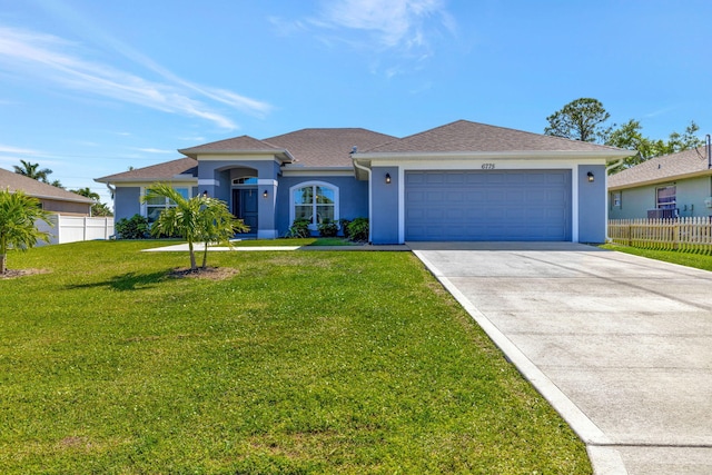 view of front of property featuring an attached garage, concrete driveway, a front yard, and fence