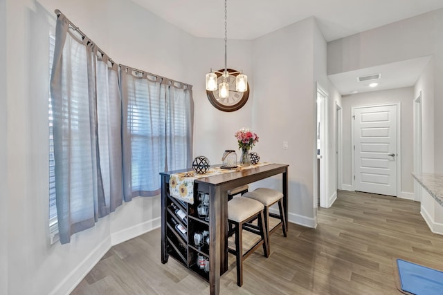 dining room featuring visible vents, baseboards, light wood-style floors, and an inviting chandelier