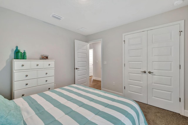 carpeted bedroom featuring baseboards, visible vents, and a closet