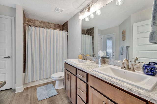 bathroom featuring double vanity, visible vents, wood finished floors, and a sink