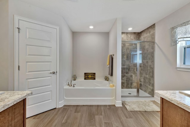 bathroom featuring a stall shower, vanity, a garden tub, and wood finished floors