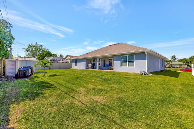 back of house featuring stucco siding, a yard, and fence