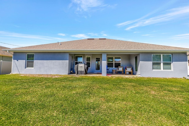 rear view of property featuring a yard, a patio area, and stucco siding