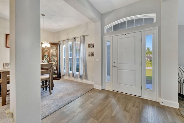 foyer entrance featuring a notable chandelier, wood finished floors, baseboards, and a healthy amount of sunlight