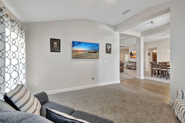 carpeted living area with visible vents, baseboards, wood finished floors, and vaulted ceiling