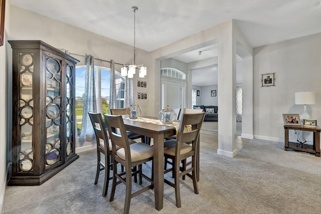 dining space with carpet flooring, baseboards, and a chandelier