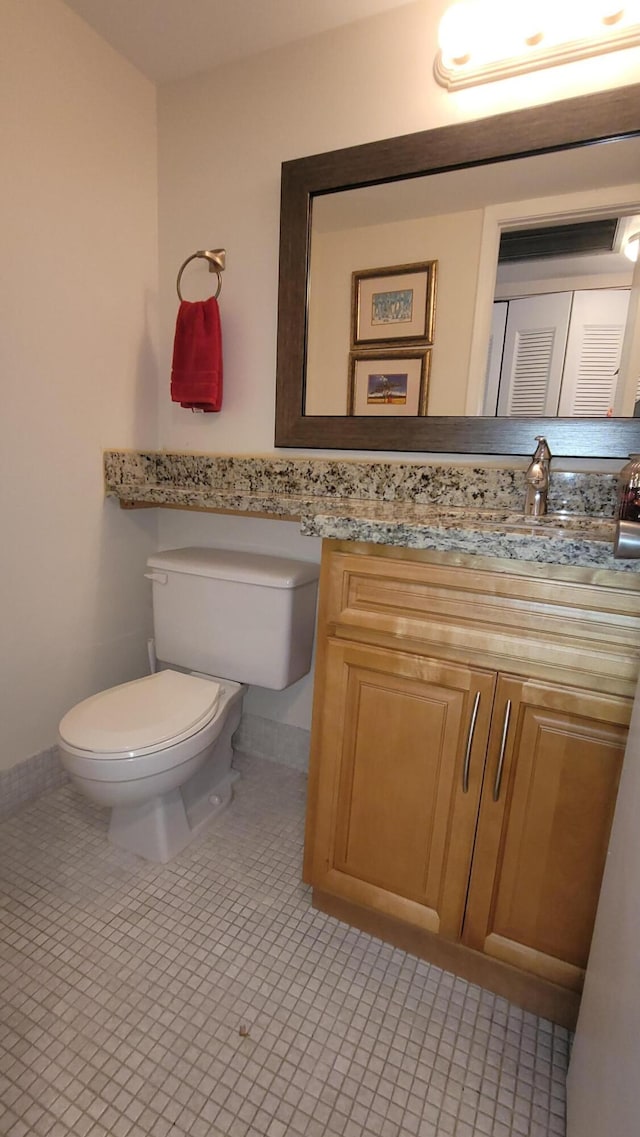half bathroom with toilet, vanity, tile patterned flooring, and baseboards