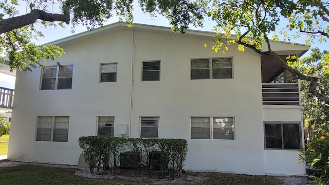 rear view of property with stucco siding and central AC unit