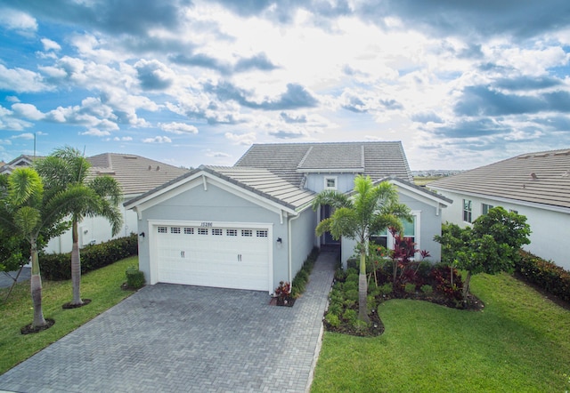 view of front of home featuring decorative driveway, a garage, a front lawn, and stucco siding