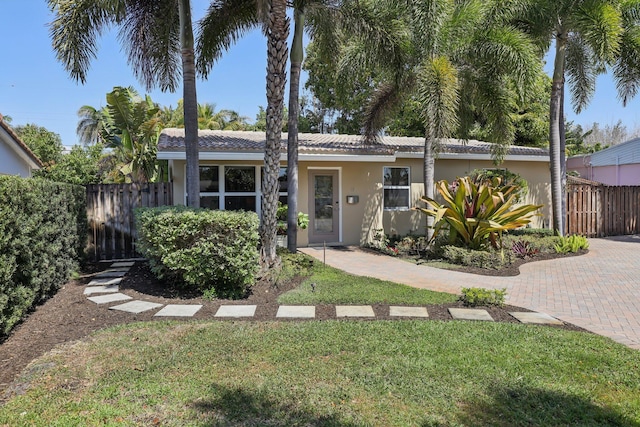 view of front of house featuring stucco siding, a front lawn, and fence