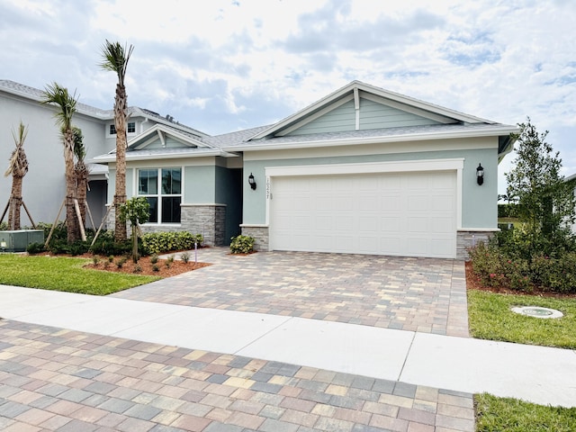 view of front of house featuring stone siding, stucco siding, decorative driveway, and a garage