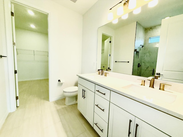 bathroom featuring a marble finish shower, toilet, a walk in closet, and a sink