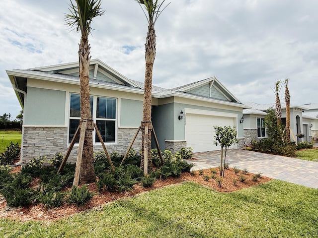 view of front of property featuring a front yard, an attached garage, stucco siding, stone siding, and decorative driveway