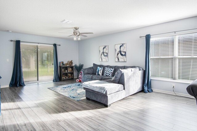 living area with visible vents, baseboards, a textured ceiling, and wood finished floors