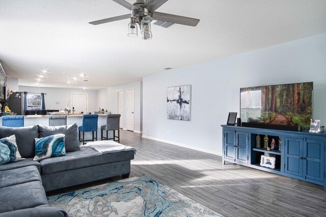 living area with visible vents, wood finished floors, baseboards, and a textured ceiling