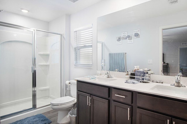 full bathroom with double vanity, a stall shower, toilet, and a sink