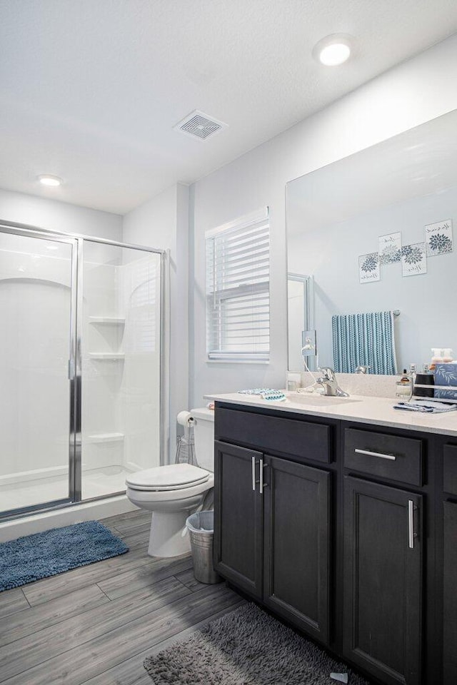 full bathroom with vanity, wood finished floors, visible vents, a shower stall, and toilet