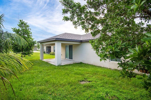 back of property featuring a patio area, stucco siding, a shingled roof, and a yard