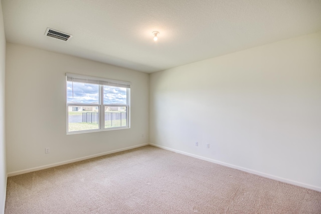 unfurnished room featuring visible vents, baseboards, and light colored carpet