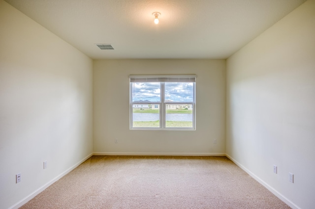 spare room with visible vents, baseboards, and light colored carpet