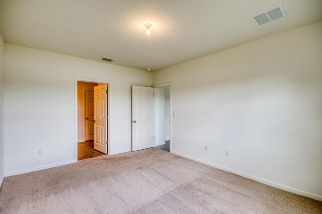 unfurnished bedroom with visible vents, carpet flooring, and baseboards