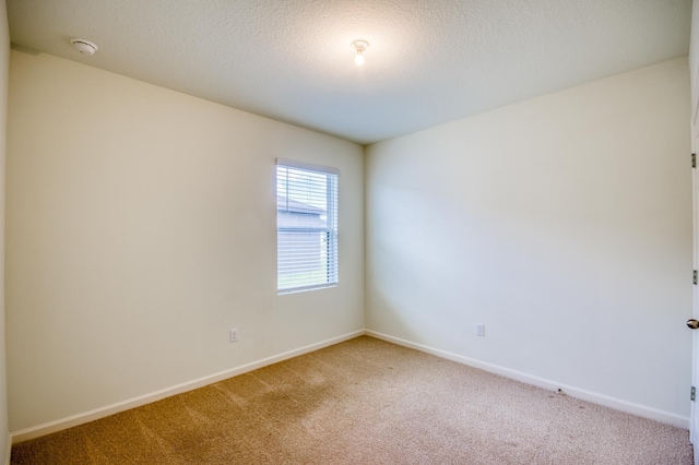 empty room with carpet, baseboards, and a textured ceiling