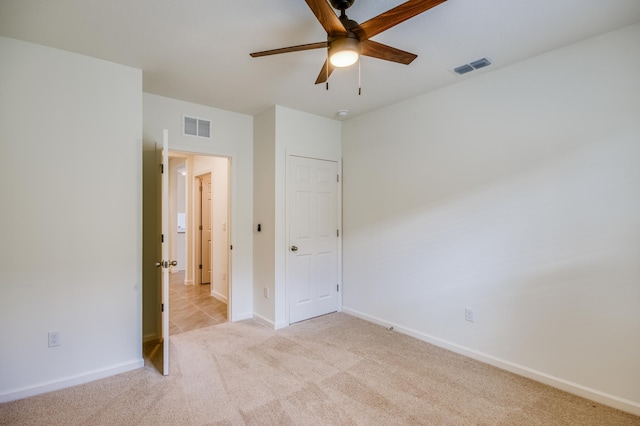 unfurnished bedroom with visible vents, baseboards, light colored carpet, and a ceiling fan