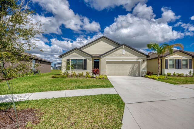 view of front of home with a front yard, an attached garage, driveway, and stucco siding