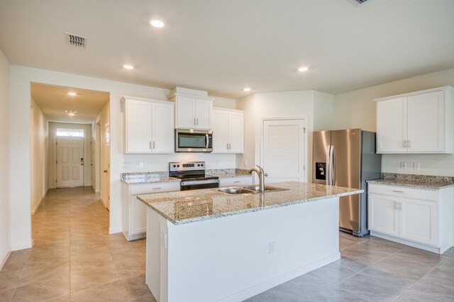 kitchen with visible vents, an island with sink, stainless steel appliances, white cabinetry, and a sink