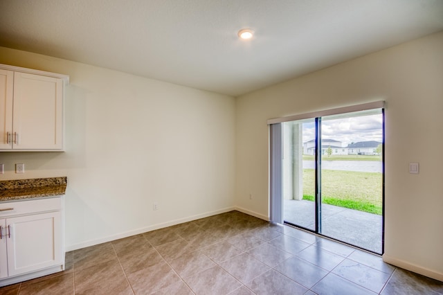 unfurnished room with light tile patterned floors and baseboards