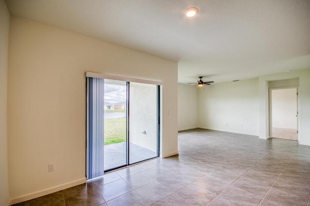 empty room with light tile patterned floors, a ceiling fan, and baseboards