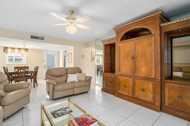 living room featuring ceiling fan, visible vents, a textured ceiling, and light tile patterned flooring