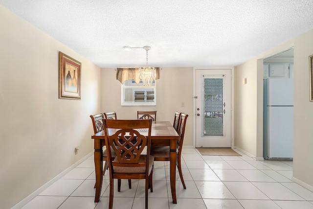 dining area with an inviting chandelier, light tile patterned flooring, baseboards, and a textured ceiling