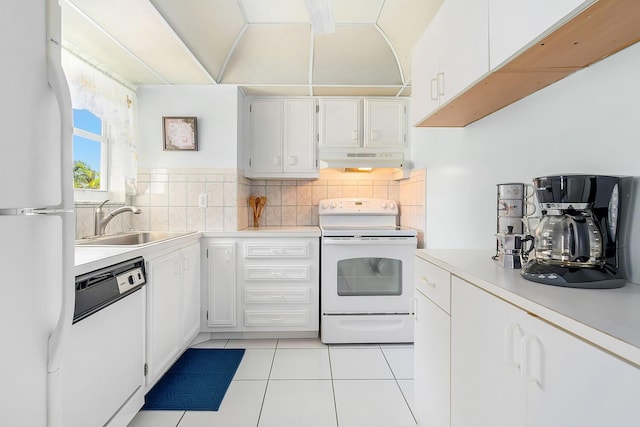 kitchen featuring under cabinet range hood, backsplash, white appliances, and light countertops