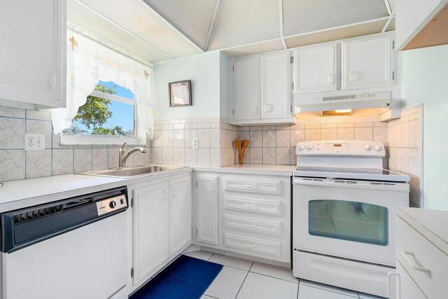 kitchen featuring under cabinet range hood, white appliances, white cabinetry, and a sink