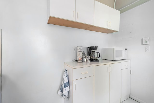 interior space featuring white microwave, white cabinets, and light countertops