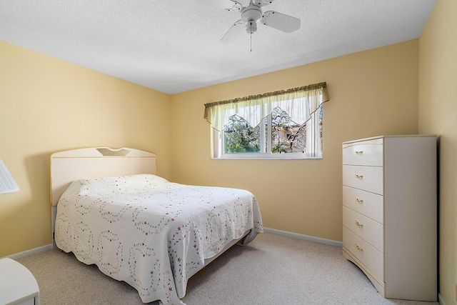 bedroom featuring baseboards, light carpet, and a textured ceiling