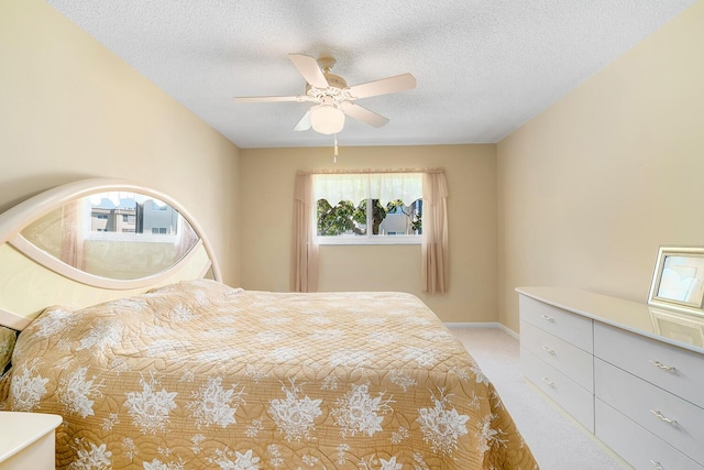 unfurnished bedroom featuring light carpet, baseboards, a textured ceiling, and ceiling fan