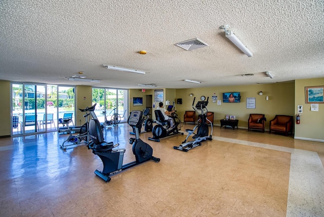 exercise room with tile patterned floors, visible vents, a textured ceiling, a wall of windows, and baseboards