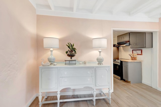 room details with wood finished floors, baseboards, stainless steel electric range, under cabinet range hood, and beamed ceiling